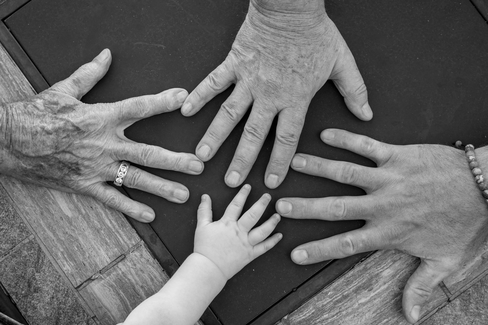 Hands of four family members of different generations resting together