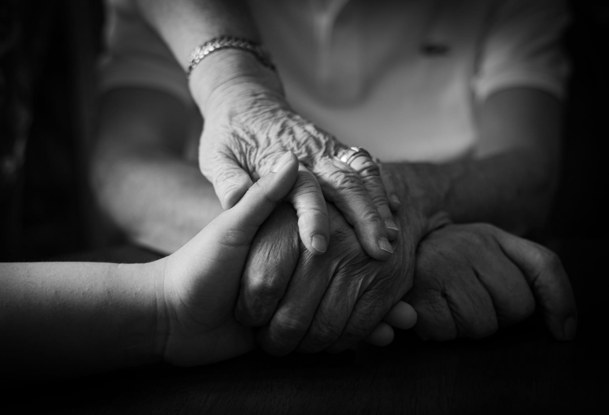 A younger pair of hands holding an older person's hands